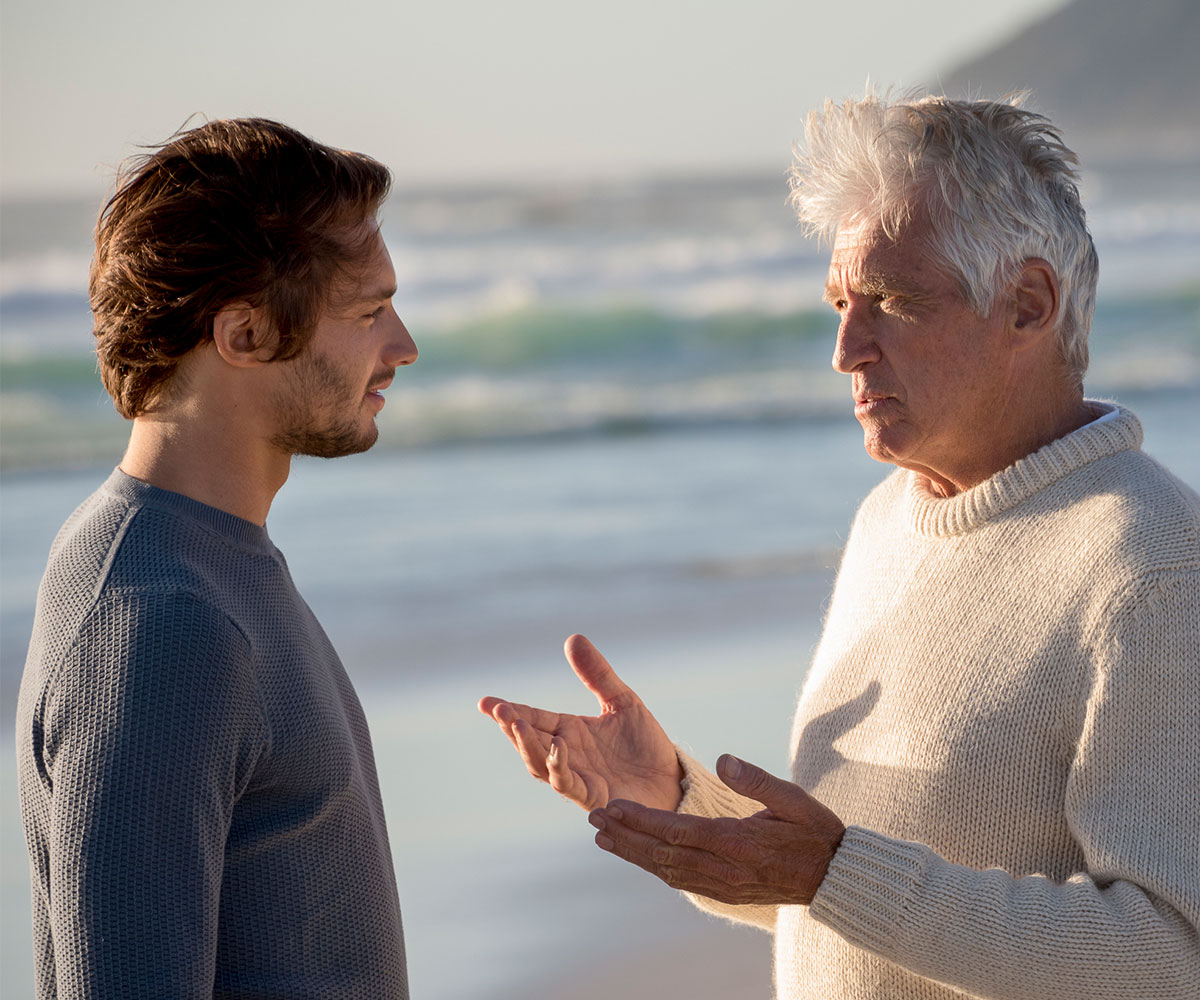 Happy father and son talking on the beach 