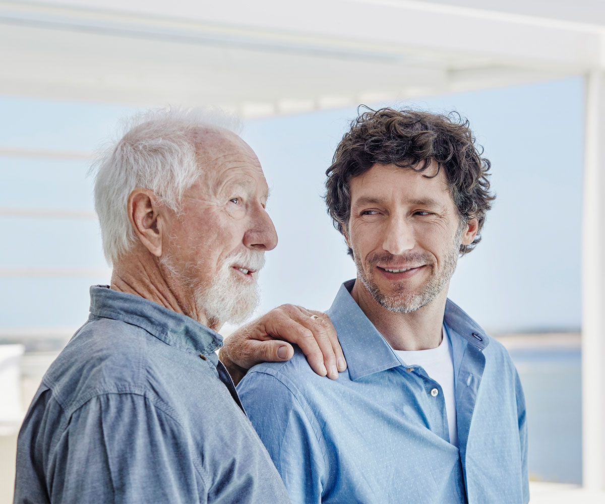 Portrait of a senior man with adult son at a beach house